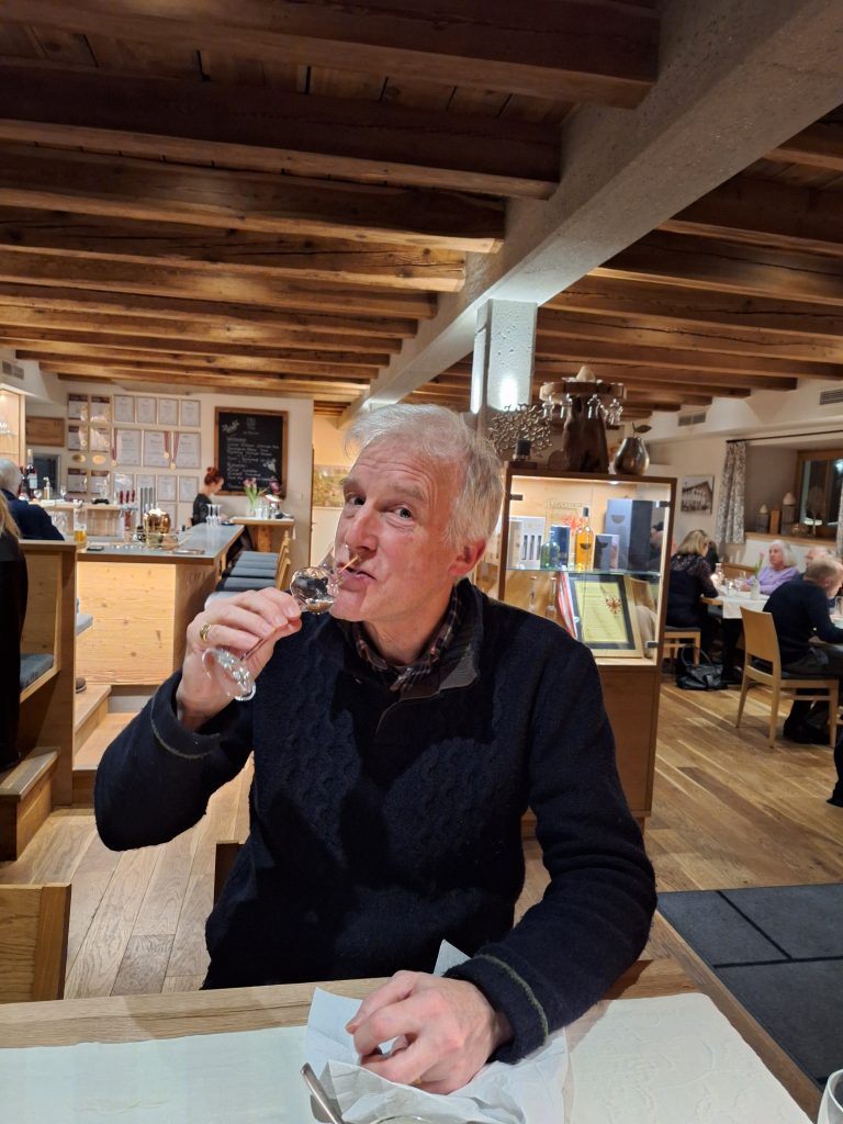 Hochformat; Mann an einem Tisch im Restaurant, trinkt aus einem Schnapsglas