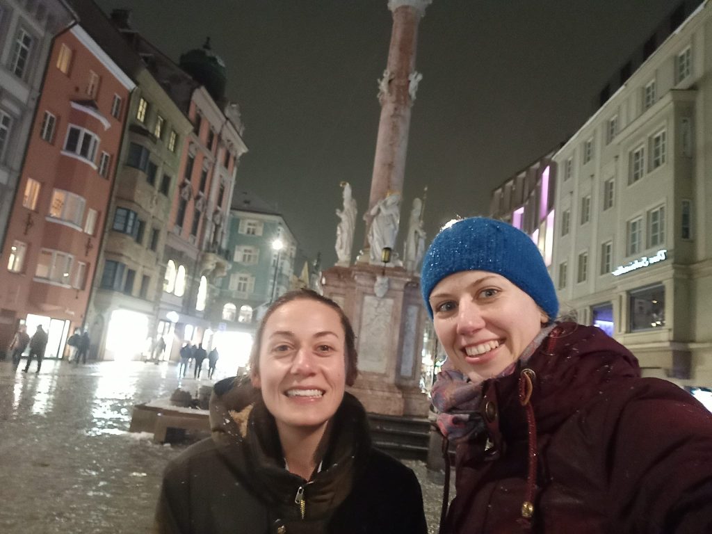Querformat; Selfie zweier Frauen; Abend, Schnee- und Regenwetter; im Hintergrund beleuchtete Häuser
