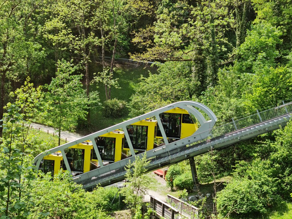 landscape format; yellow funicular car on a slanted track; from the side; in the woods
